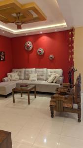 a living room with red walls and a couch and tables at Seneh Homes in Guwahati