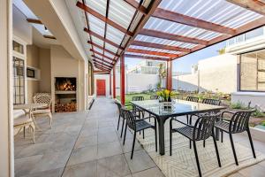 a patio with a table and chairs and a fireplace at HOME-LYNN, 4 bedroom, Bloubergstrand in Bloubergstrand