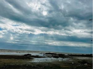 un ciel nuageux sur l'océan sur une plage dans l'établissement Cozy Madh Island Cottage with Private Courtyard, à Jāmb