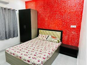 - une chambre avec un mur rouge et un lit dans l'établissement Cozy Madh Island Cottage with Private Courtyard, à Jāmb