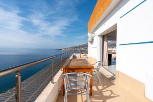 Duplex penthouse في Polisi i Vogël: شرفة مع طاولة وكراسي خشبية والمحيط