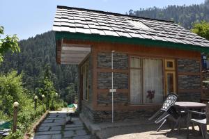 a small cabin with a table and chairs in front of it at Himalayan Pine Majesty in Jibhi