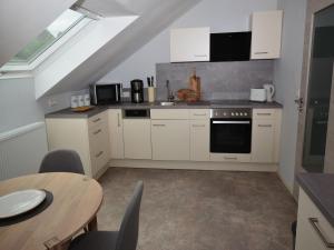 een keuken met witte kasten en een tafel met stoelen bij Ferienwohnungen Ambiente-Schmidt in Wiemeringhausen