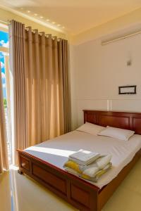 a bedroom with a bed with white sheets and a window at Kathy Hotel in Ho Chi Minh City