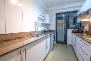 Roches NoiresにあるAzuri Ocean & Golf Village - Elegant 3-Bedroom Apartment with Private Garden, Beach & Pool Access in Roches Noiresの白いキャビネットとシンクのあるキッチン +8枚の写真