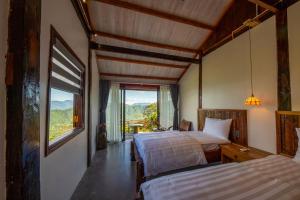 a bedroom with two beds and a large window at SIM Farmstay in Ha Giang