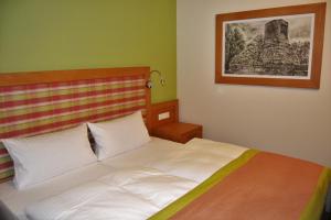 ein Schlafzimmer mit einem weißen Bett mit einem Bild an der Wand in der Unterkunft Hotel & Restaurant Waldcafe Hettstedt in Hettstedt
