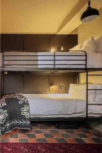 a bedroom with a bunk bed with white sheets at BOHOSTEL in Macclesfield