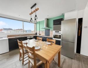 a kitchen with a wooden table with chairs and a refrigerator at Vue mer imprenable à Dunkerque, l'appel du large! in Dunkerque