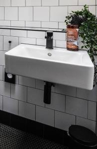 a white sink in a bathroom with a plant at BOHOSTEL in Macclesfield