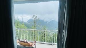 a window with two chairs on a balcony with a view at Dreamy Delight in Nathia Gali