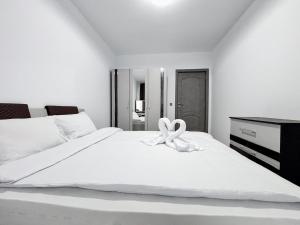 un lit blanc avec un nœud dessus dans l'établissement Julia Airport Apartment With Parking, à Someşeni
