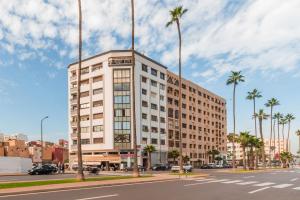 a tall white building on a city street with palm trees at Appartement Cosy et central in Casablanca