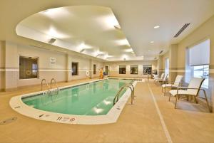 a swimming pool in a hotel room with chairs at Holiday Inn Express & Suites Utica by IHG in Utica