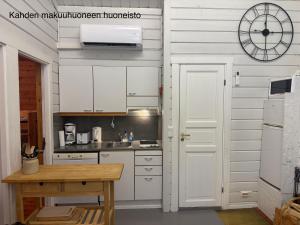 a kitchen with white cabinets and a clock on the wall at Messner Tahko parimökki - Saunallinen ja saunaton huoneisto - in Tahkovuori