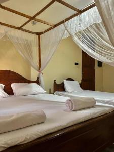 two beds in a bedroom with white drapes at Kurundu House Mirissa in Mirissa