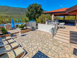 een terras met stoelen en een zwembad bij Dvori Stipanovi with heated pool and jacuzzi in Donje Rašćane