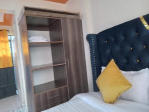 a bed with a blue headboard next to a book shelf at Flomark in Ngong