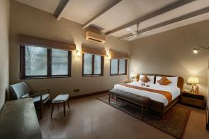 a bedroom with a bed and a chair and windows at Kashe Benaras in Varanasi +32 photos