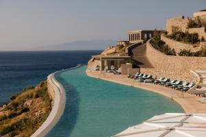 Una piscina con sillas y sombrillas junto al mar. en Cali Mykonos, en Kalafatis 75 fotos más
