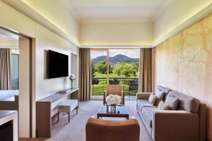 a living room with a couch and a television at Hôtel Barrière Ribeauvillé in Ribeauvillé