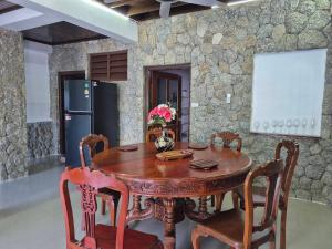 een houten tafel en stoelen in een kamer met een stenen muur bij Nur Nur House in Ban Nong Chaeng