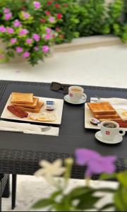 a table with two plates of food and cups of coffee at Villaasa in Shaviyani Atoll