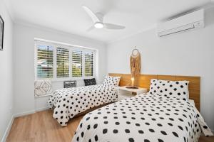 two beds in a bedroom with white walls and a window at Spacious, 2 bedroom Townhouse in Noosaville Resort in Noosaville +20 photos