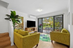 a living room with two yellow couches and a tv at Spacious, 2 bedroom Townhouse in Noosaville Resort in Noosaville