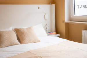 a bed with white sheets and pillows next to a window at Kaisercity Apartment 2 in Nuremberg +9 photos