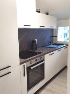 eine Küche mit weißen Schränken und einem Herd mit Backofen in der Unterkunft Sweet Home Longarone in Longarone