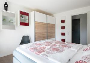 a white bedroom with a large white bed with red accents at Ferienwohnung Wellenreiter mit ruhigem Garten in Überlingen