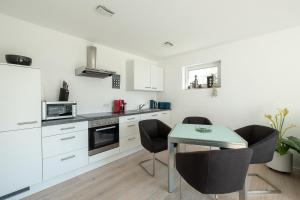 a kitchen with white cabinets and a table and chairs at Ferienwohnung Wellenreiter mit ruhigem Garten in Überlingen