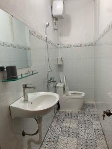 Un baño blanco con lavabo e inodoro. en Homestay Rừng Phố 2 - Măng Đen, en Kon Plong