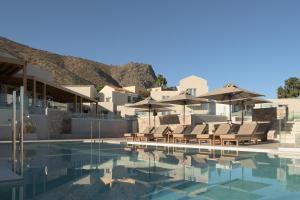 a swimming pool with lounge chairs and umbrellas at Galaxy Suites Boutique Resort in Hersonissos