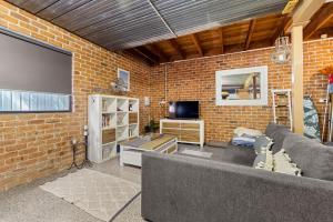 a living room with a couch and a brick wall at Holiday Retreat Jervis Bay - 5 Min Walk to Bay in Callala Bay