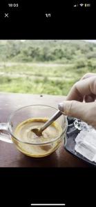 una persona revolviendo un tazón de comida con una cuchara en Homestay Rừng Phố 2 - Măng Đen, en Kon Plong