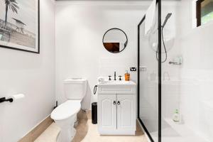 a white bathroom with a toilet and a shower at Holiday Retreat Jervis Bay - 5 Min Walk to Bay in Callala Bay +26 photos