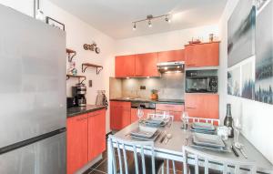 a kitchen with orange cabinets and a table with chairs at Amazing Apartment In De Haan With Wifi in Mispelburg