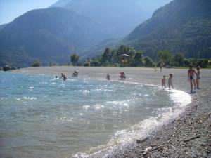 a group of people playing in the water on a beach at Garnì Lago Alpino in Molveno
