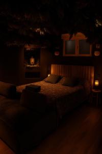 a dark bedroom with a bed and a couch at Jungle Room Strasbourg - Évasion Tropicale - Sauna Jacuzzi Balnéo in Strasbourg