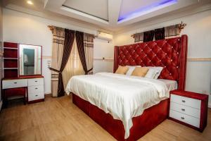 a bedroom with a large bed with a red headboard at A Luxury 3 bedroom bungalow in Owerri