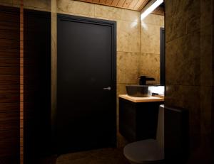 une salle de bain avec toilettes et porte noire dans l'établissement Raitola Reindeer and Husky Farm- Panorama Lodges, à Rovaniemi
