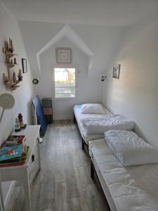 a bedroom with two beds and a desk and a window at Maison en pierre accès 5 mn à pied plage in Arzon