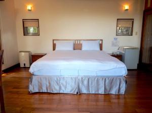 Un dormitorio con una gran cama blanca en una habitación. en 鳳凰森之鳴, en Lugu