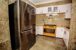 a kitchen with a stainless steel refrigerator and white cabinets at A Luxury 3 bedroom bungalow in Owerri +14 photos