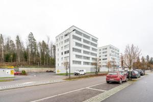 a red car parked in a parking lot next to a building at Hiisi Homes Klaukkala in Klaukkala