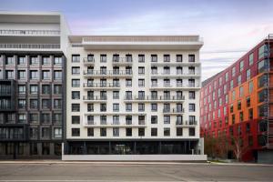 a white building with red buildings in front of it at BABEL COMMUNITY Hôtel Saint-Quentin-en-Yvelines in Montigny-le-Bretonneux
