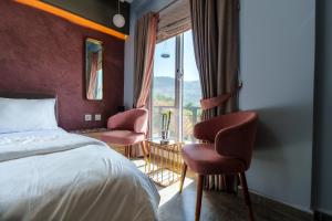 une chambre avec un lit et deux chaises et une fenêtre dans l'établissement Murree Hills Executive 3 Bedroom Cottage with Scenic View, à Murree