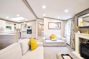 a living room with white furniture and yellow pillows at Sunbird Lodge with Hot Tub in York